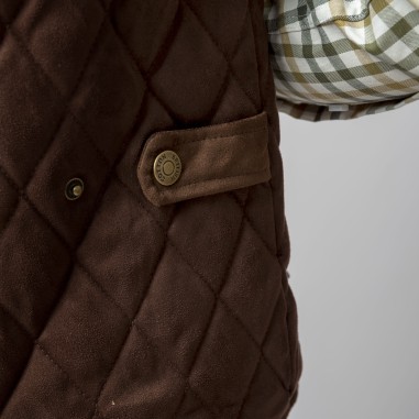 Detalhe de tecido castanho acolchoado e botão metálico junto com camisa xadrez