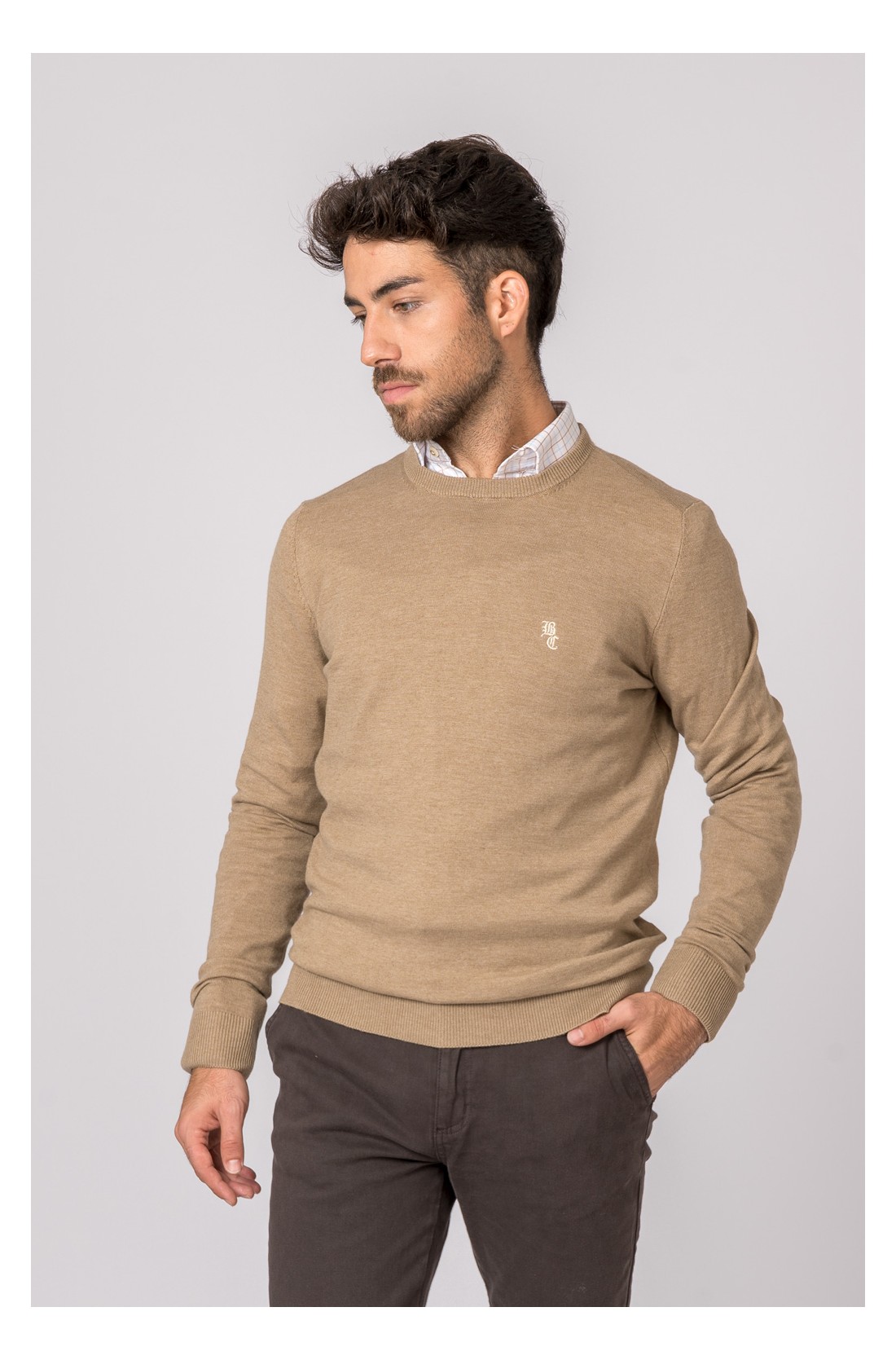 Homem a usar camisola bege de manga comprida e gola redonda com camisa branca por baixo