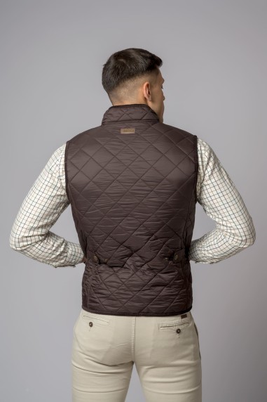 Homem de costas a usar colete castanho matelassê e camisa xadrez