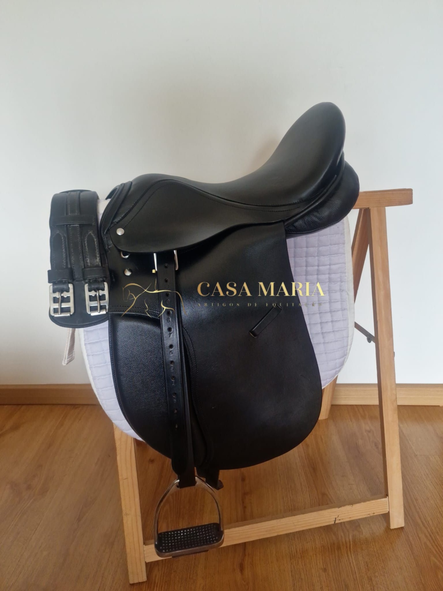 Sela de equitação preta de couro sobre suporte de madeira