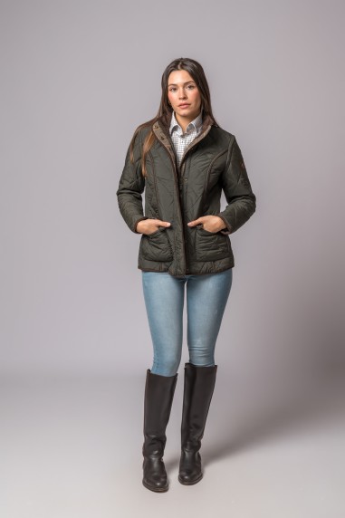 Mulher com casaco verde escuro acolchoado, camisa xadrez, jeans azuis claros e botas pretas