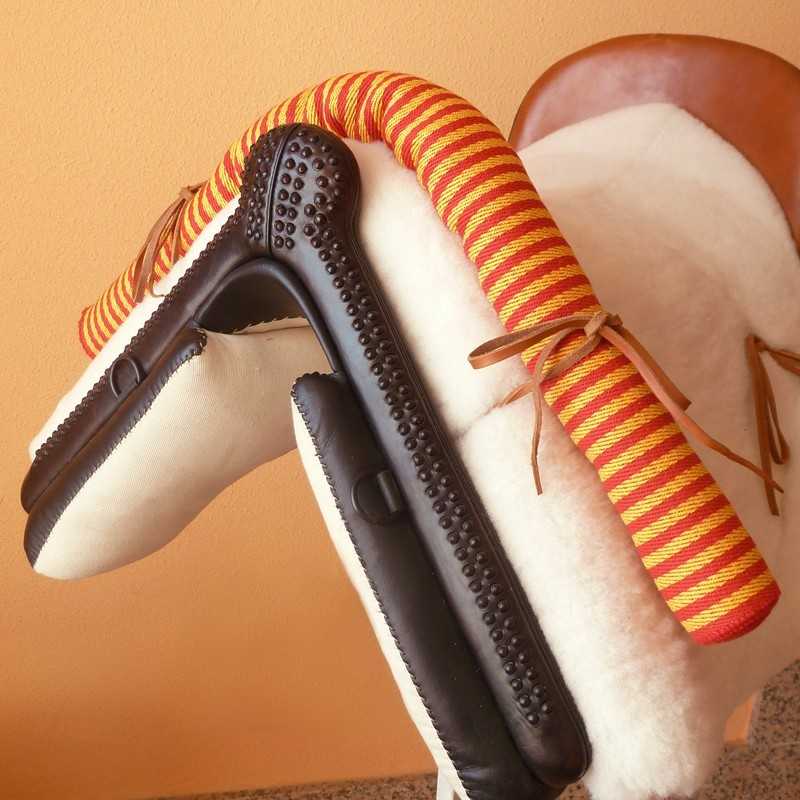 Brinquedo de cavalo de pau infantil com tecido branco peludo e detalhes em tecido listrado amarelo e vermelho.