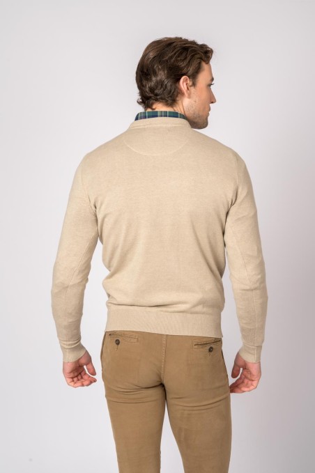 Homem de costas com camisola bege, camisa xadrez e calças castanhas