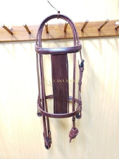 Cabeçada de couro castanha pendurada num cabide de madeira