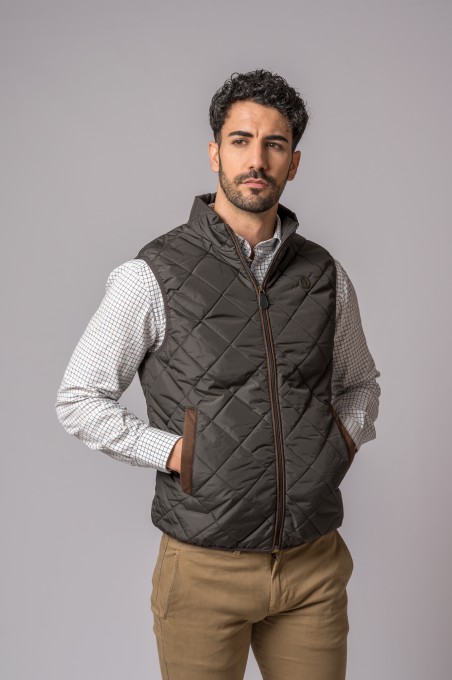 Colete masculino castanho escuro acolchoado com camisa branca e fundo cinzento