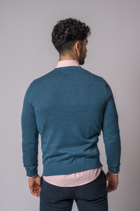 Homem visto de costas a usar camisola azul petrol de malha e camisa de riscas