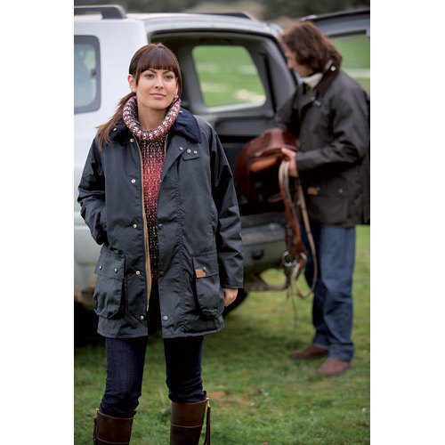 Mulher com casaco impermeável preto junto a jipe branco em relvado