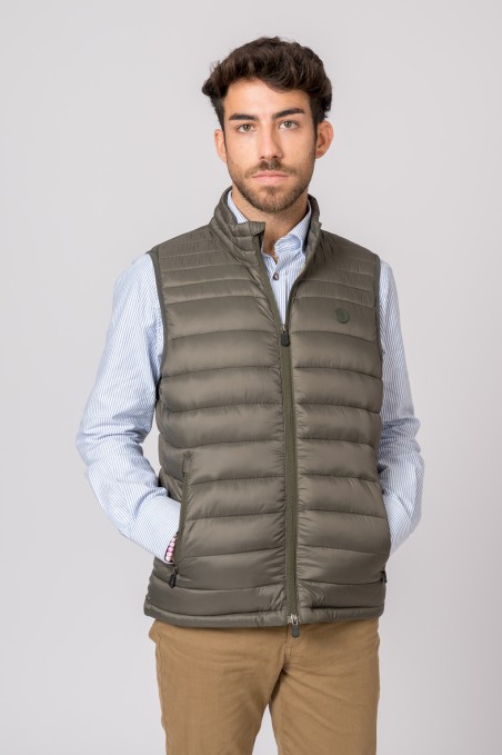 Colete masculino verde-oliva acolchoado com camisa azul às riscas e calças castanhas