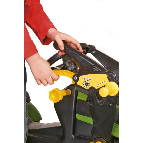 Mãos de criança a manusear trator de brinquedo preto, amarelo e verde