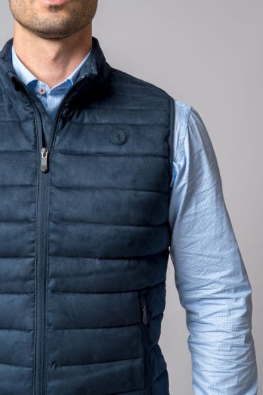 Colete masculino azul escuro acolchoado sobre camisa azul clara quadriculada