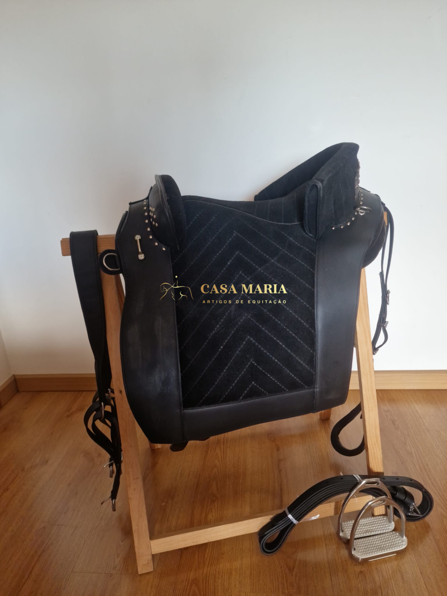 Sela de equitação preta com suportes de madeira e estribos