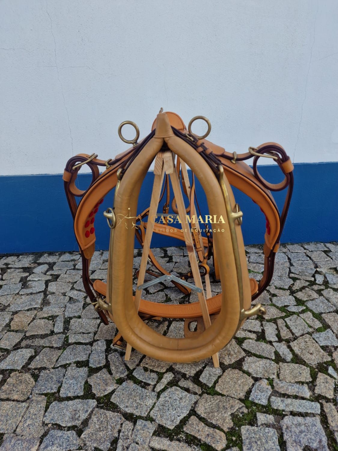 Arreio de couro castanho com metal dourado em suporte de madeira