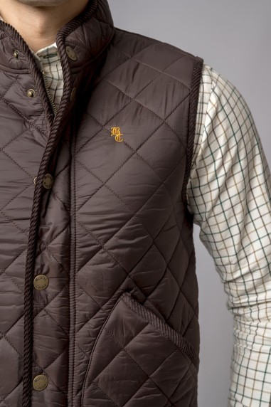 Colete acolchoado castanho escuro com bordado RL usado sobre camisa xadrez branca e preta