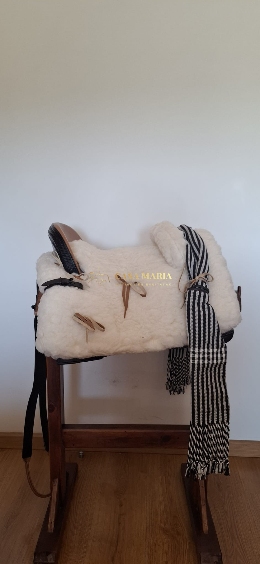 Sela branca felpuda com manta preta e branca em banco de madeira