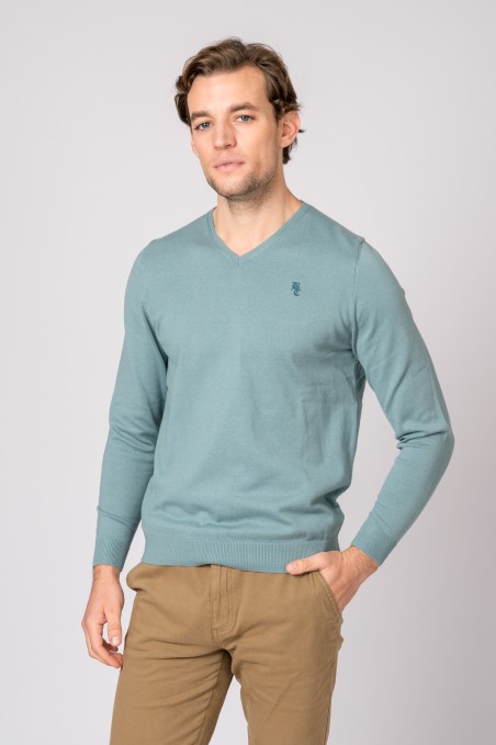 Homem com camisola azul clara de malha e calças castanhas