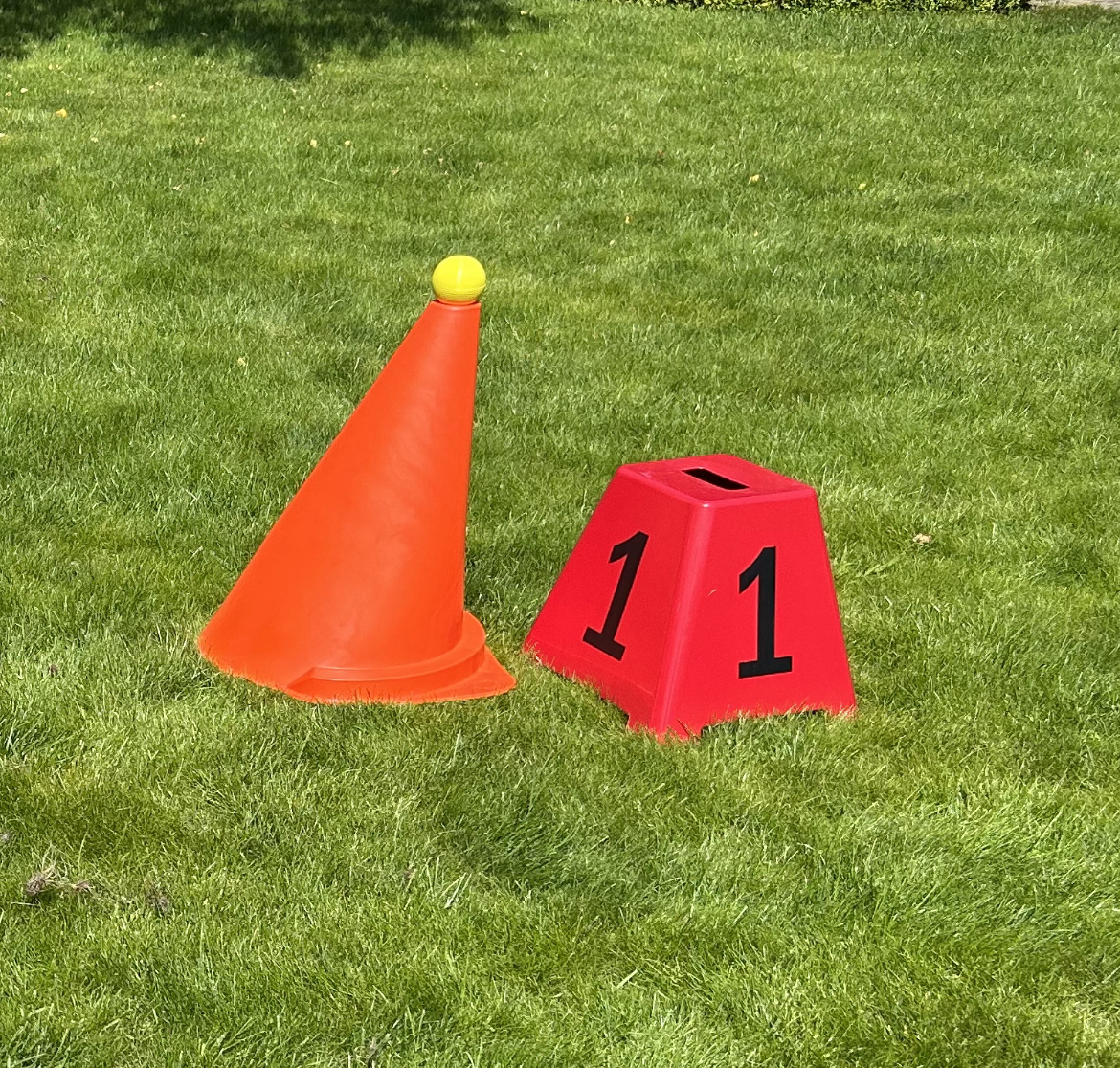 Cone de sinalização laranja com bola amarela e peça vermelha com número 11 em relvado