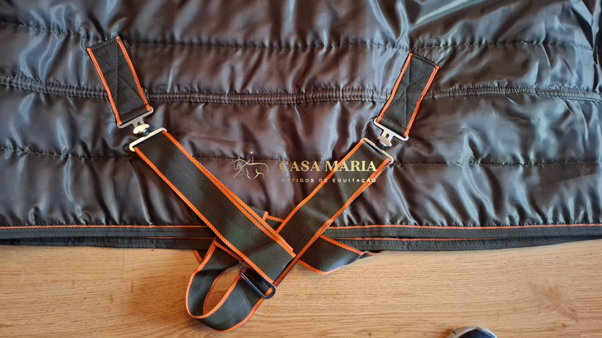 Cobertor para cavalo preto com bandas elásticas pretas e detalhes em laranja.