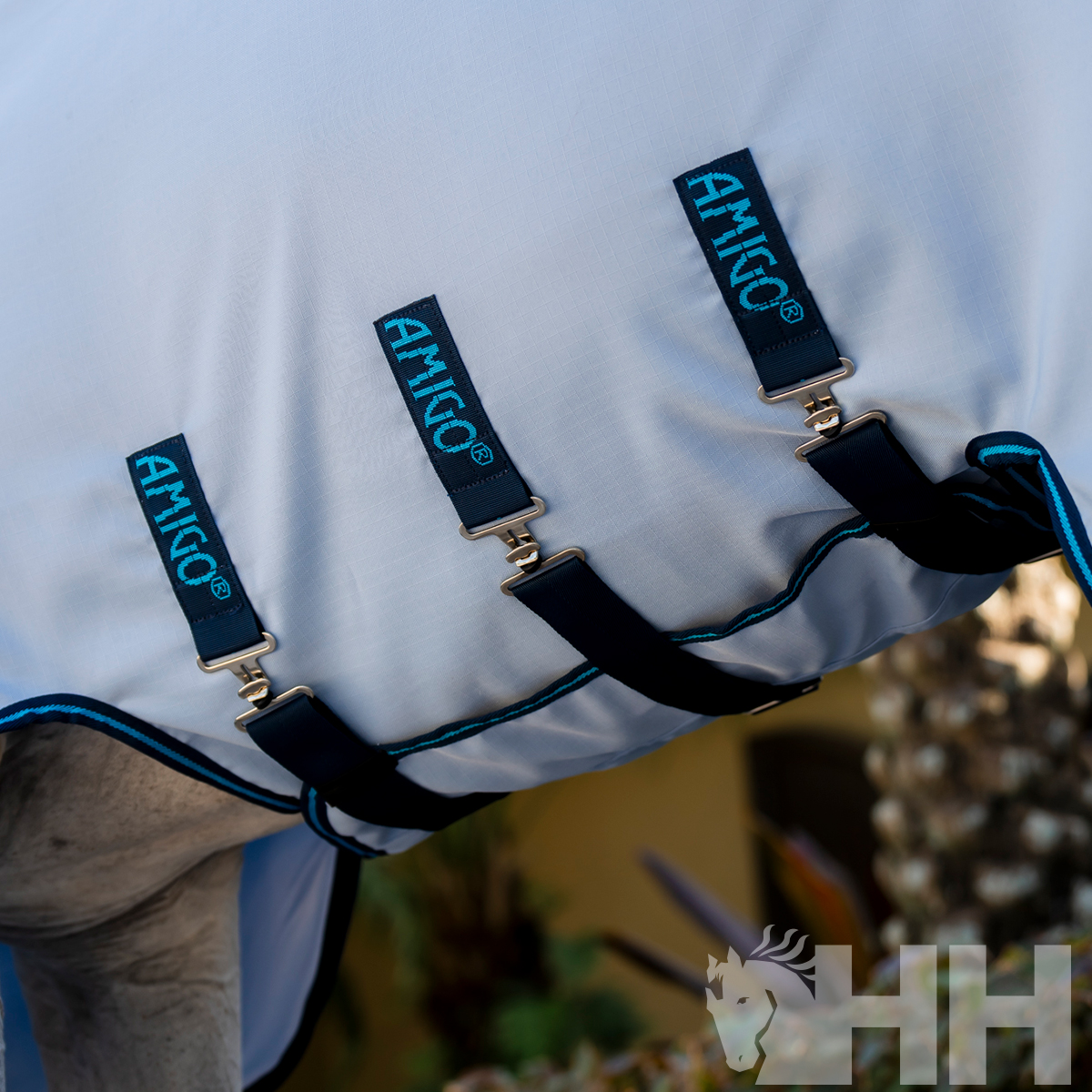 Produto têxtil branco com acabamentos azuis e fivelas com etiquetas AMIGO®