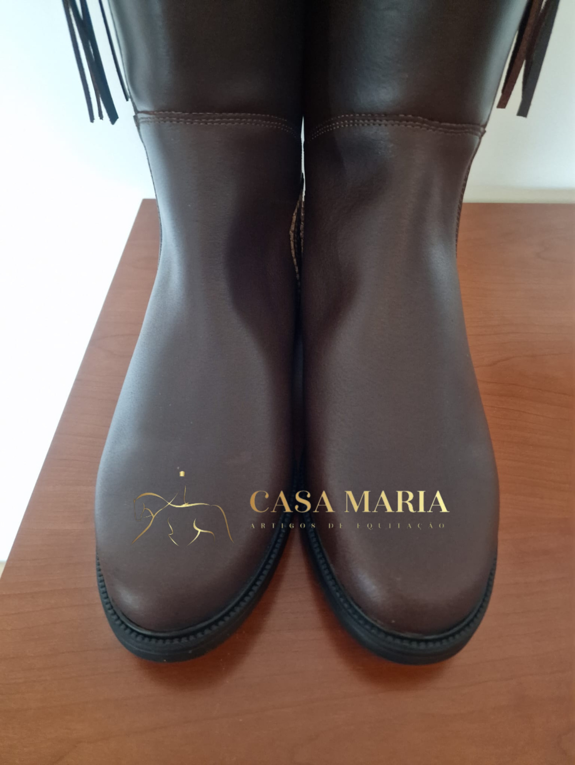 Botas de couro castanho escuro em superfície de madeira