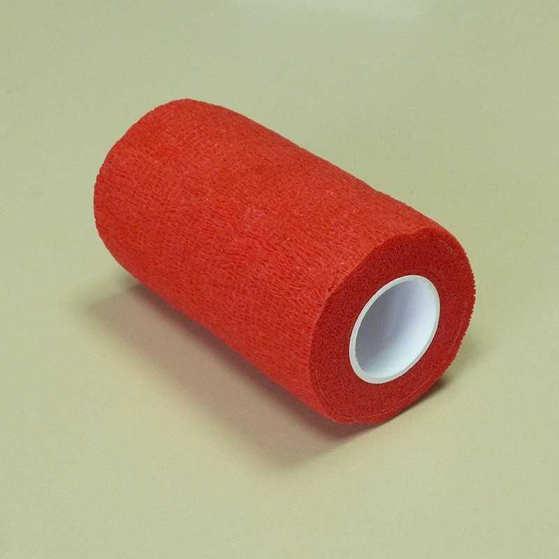 Rolo de fita adesiva vermelha com núcleo branco sobre superfície bege