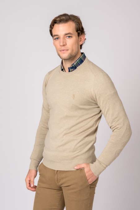 Homem a usar camisola bege de malha fina com camisa xadrez verde e azul e calças castanhas.