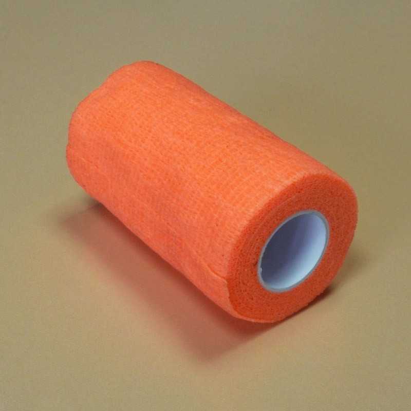 Rolo de fita adesiva ou bandagem elástica laranja com núcleo branco sobre superfície bege