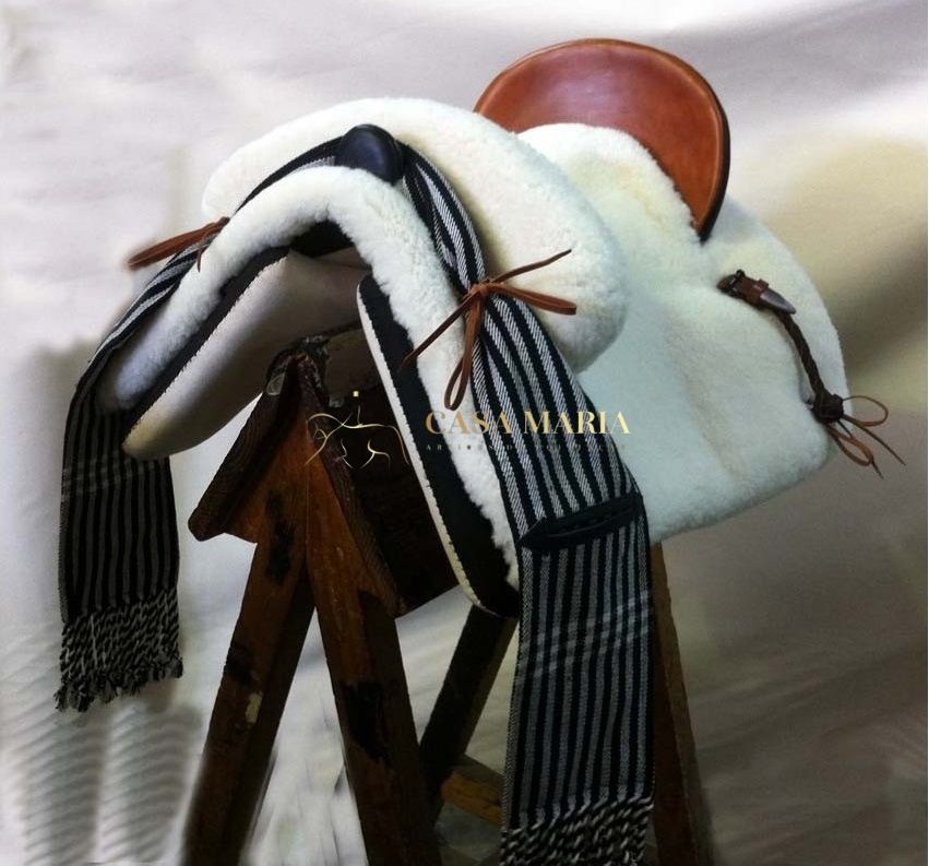 Sela de equitação branca com detalhes castanhos e echarpe preta e branca às riscas