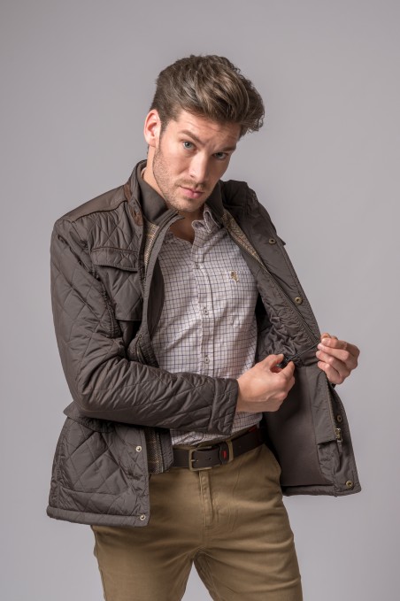 Homem vestindo casaco acolchoado bege escuro com camisa xadrez e calças castanhas