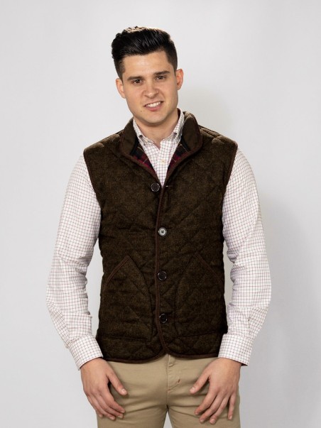 Homem com colete castanho acolchoado e camisa xadrez branca com vermelho