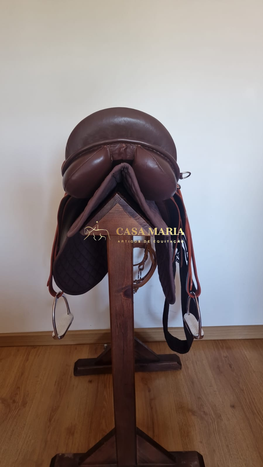 Sela de equitação castanha em suporte de madeira