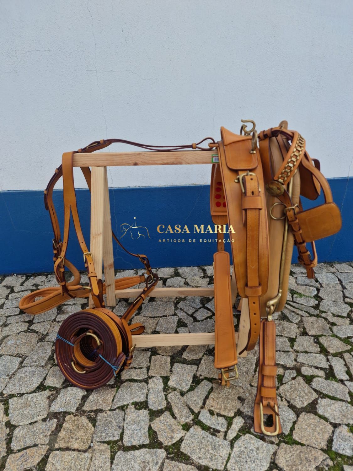 Conjunto de artigos equestres em cabedal castanho sobre suporte de madeira