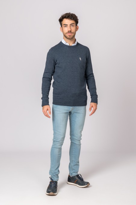 Homem com camisola azul escura, calças de ganga e sapatilhas escuras