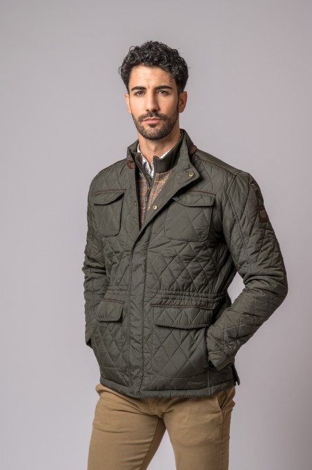 Casaco masculino acolchoado verde-oliva com bolsos e botões, usado por modelo de pé com fundo cinza claro.
