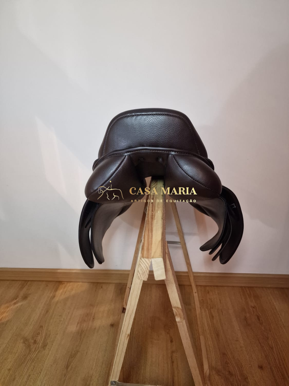 Sela preta de couro sobre suporte de madeira com texto CASA MARIA ARTEDE DE COUTURAÇÃO