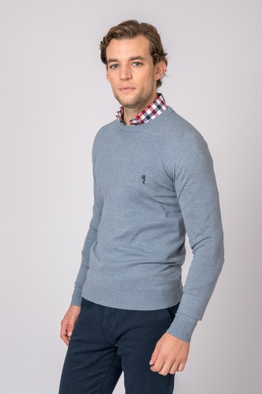 Homem com camisola azul clara e camisa xadrez com calças azul-escuras