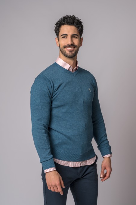 Homem com camisola azul de malha e camisa de riscas rosa e branca