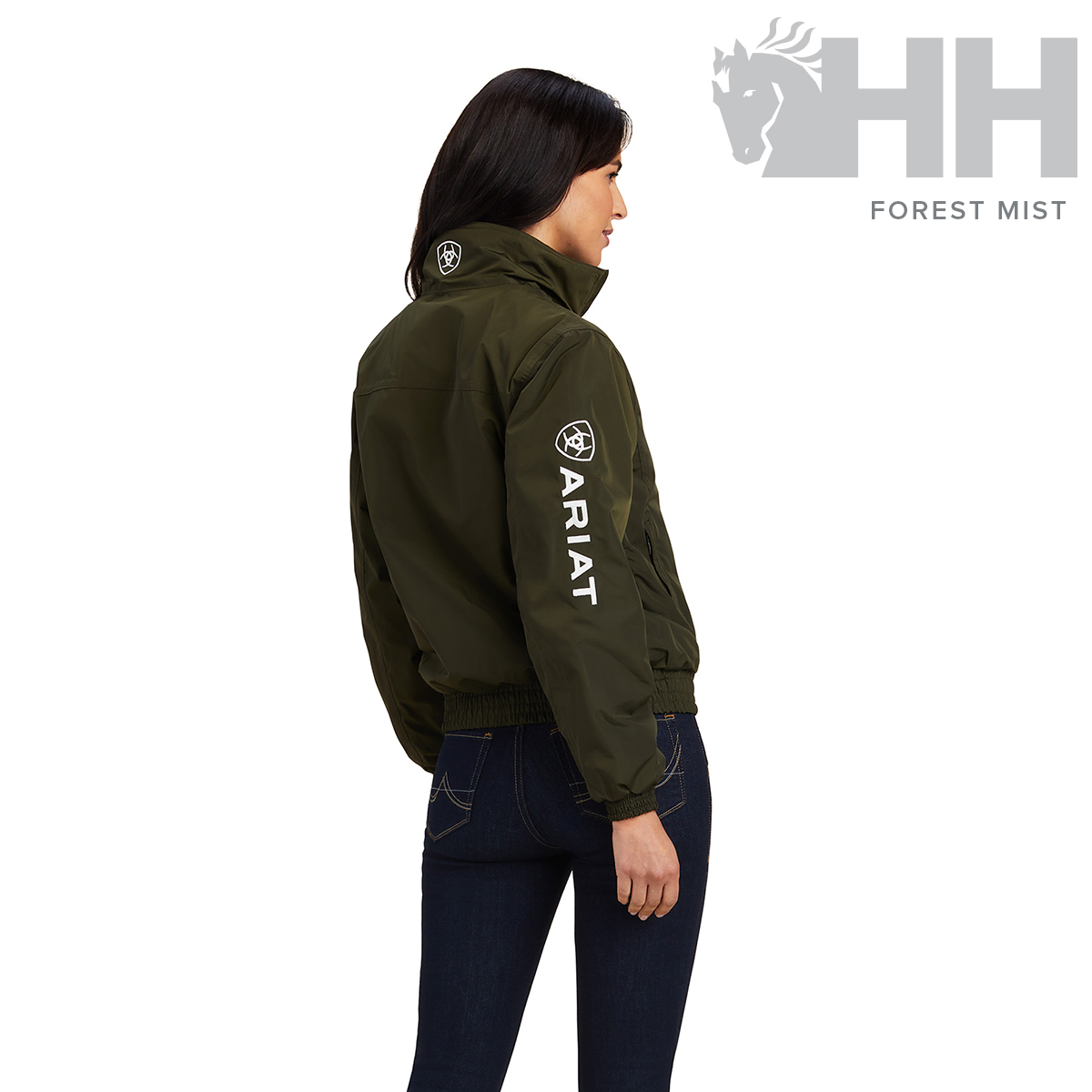 Blusão verde escuro com logótipo ARIAT na manga, usado por mulher de costas.