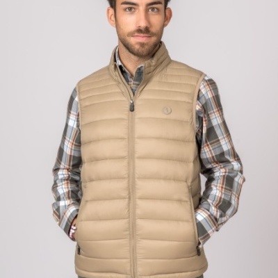 Homem a usar colete acolchoado bege sobre camisa xadrez e calças verdes