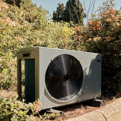 Unidade externa de ar condicionado ou bomba de calor cinzenta com ventoinha preta num jardim