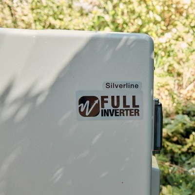 Parte lateral de aparelho branco com etiquetas Silverline e FULL INVERTER ao ar livre