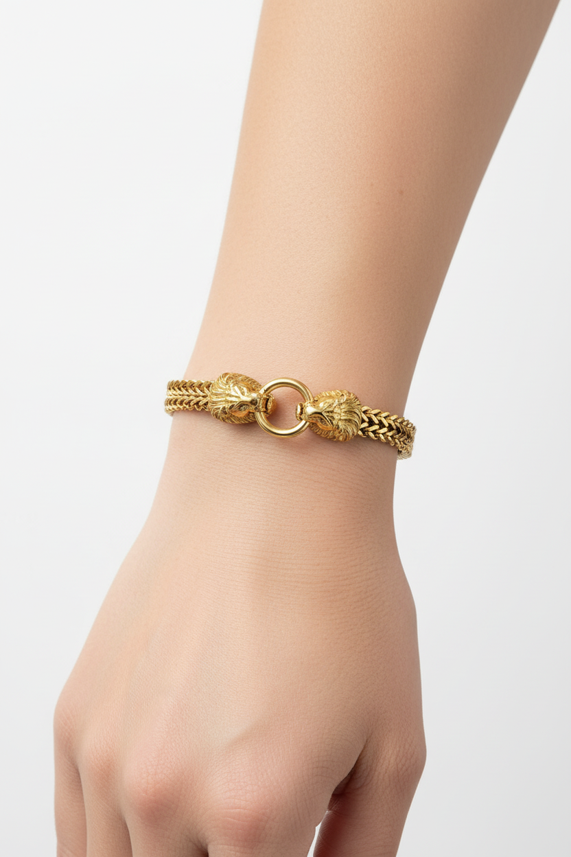 Pulseira dourada com elos e cabeças de animal no fecho usada no pulso