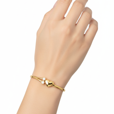 Pulseira dourada com coração e brilhantes no pulso