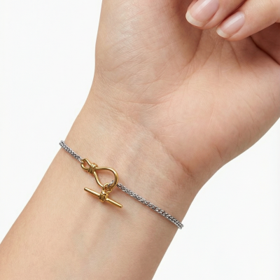 Pulseira com corrente prateada e fecho dourado no pulso