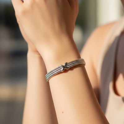 Pulseira prateada em malha fina com detalhe cruzado no pulso
