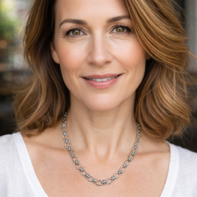 Colar de prata com elos ovais e detalhes ornamentais usado por mulher com camisola branca