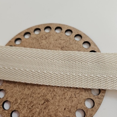 Fita têxtil creme sobre peça circular de madeira com furos