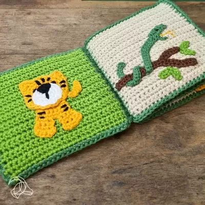 Livro infantil em croché com desenhos de tigre amarelo e cobra verde