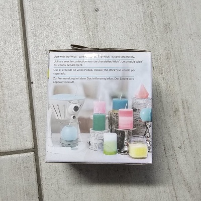 Caixa com imagem de castiçais e velas coloridas com texto multilíngue sobre o pavio Wick