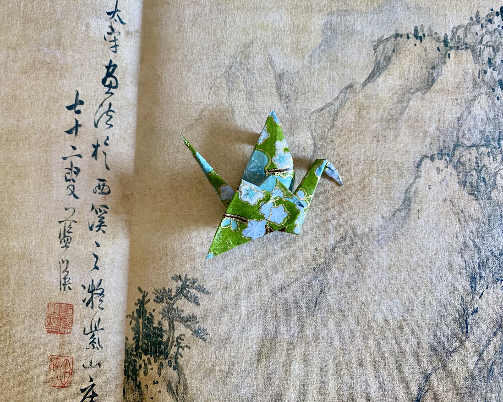 Pregadeira Tsuru Origami de pássaro em papel floral azul e verde sobre papel com gravura asiática e texto em caracteres chineses