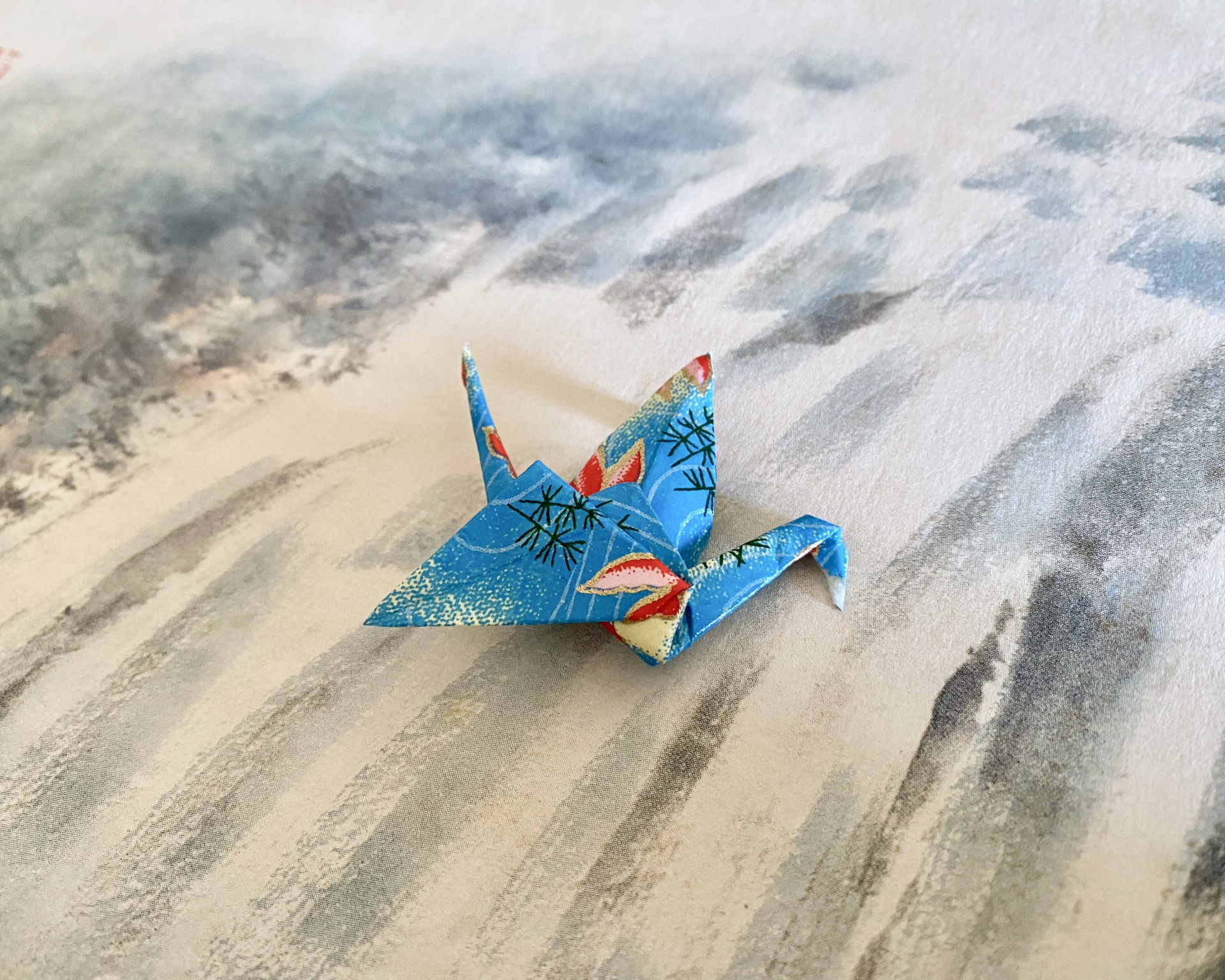 Pregadeira Tsuru Pássaro de origami azul com padrões coloridos sobre superfície cinza